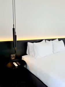 佛丕WIIN Phetchaburi วิน เพชรบุรี的卧室配有白色的床和带遥控器的桌子