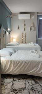 于泽什Résidence LE11B的配有2张床的带白色床单和灯的客房