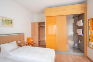 菲斯普Hotel-Restaurant Eyholz的一间带一张床和一个衣柜的小卧室