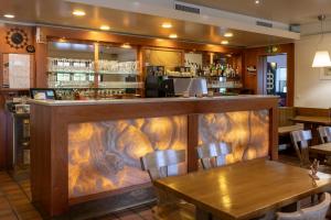 菲斯普Hotel-Restaurant Eyholz的餐厅设有木酒吧,配有桌椅