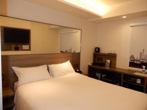 广岛Smile Hotel Hiroshima的一间卧室配有一张床和一张书桌及电视