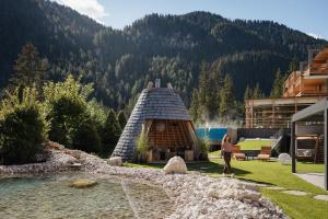 拉维拉Hotel Cristallo - Wellness Mountain Living的站在有房子的建筑物前面的人