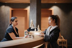 拉维拉Hotel Cristallo - Wellness Mountain Living的两个站在柜台上互相交谈的女人