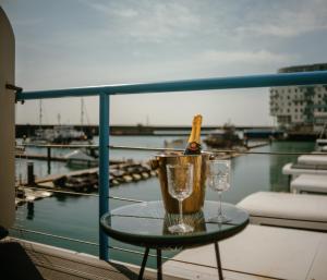 布莱顿霍夫Tiny Floating Home with Marina Views的阳台上的桌子上放有一瓶香槟和玻璃杯