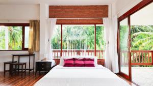 恰洛克拉姆Baan Bhuwann Holiday Apartment的卧室配有一张带粉红色枕头的大床