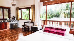恰洛克拉姆Baan Bhuwann Holiday Apartment的卧室配有带红色枕头的白色床