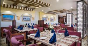 马斯喀特AL MANAF HOTEL SUITES的餐厅配有桌椅和蓝色餐巾