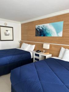 劳德代尔堡Ocean Manor Tiki Sunset Retreat的两张位于酒店客房的床,配有蓝色床单