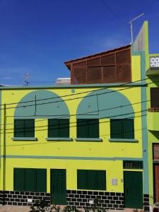 波多诺伏Residencial Chez Flor的黄色和绿色的建筑,带有棕色的屋顶