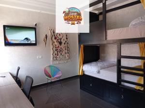 马拉喀什Stork Marrakech Luxury Hostel的一间卧室配有双层床、电视和桌子