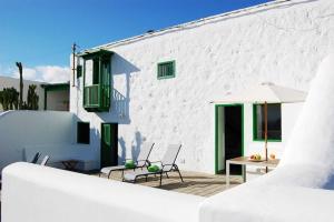 蒂亚斯Typical Canarian house with fabulous sea views的白色的建筑,设有配备椅子和遮阳伞的庭院