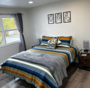安克雷奇Anchorage midtown apartment- Wyoming 1的一间卧室配有一张带条纹床单的床和窗户。