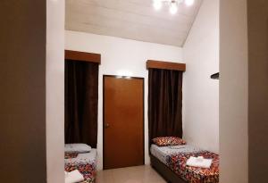 利帕Zillion Pavilion Family & Business Hotel的小房间设有两张床和一扇门
