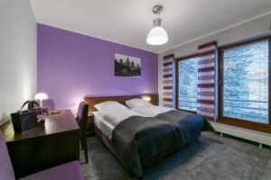 隆代克-兹德鲁伊CK卡利纳旅馆的一间卧室设有紫色的墙壁、一张床和一张书桌