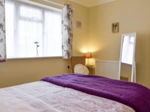 Birtsmorton莉娜山林小屋酒店的一间卧室配有一张床铺,床上铺有紫色毯子