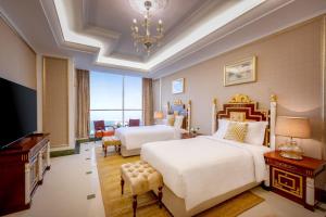 多哈Dusit Hotel & Suites - Doha的一间卧室配有两张床和一台平面电视