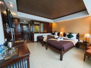 清迈Goldenbell Hotel Chiangmai的酒店客房设有两张床和电视。