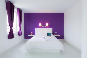金边金边诚酒店的卧室配有白色的床和紫色的墙壁