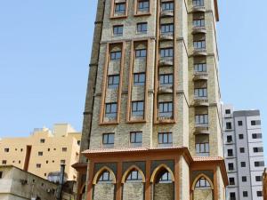 科威特Relax inn Apartment - Fahaheel的一面有窗户的高高的砖砌建筑