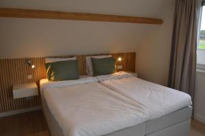 奥德多普Vakantiehuis 't Hertenkamp的卧室配有带绿色枕头的大型白色床