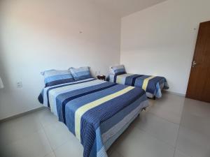 巴雷里尼亚斯Casa 22 Lençóis Maranhenses - Barreirinhas - MA的白色客房的两张床,拥有蓝色和黄色条纹