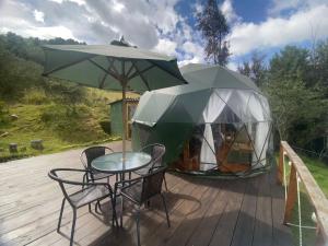 瓜塔维塔Glamping El Refugio的甲板上的桌椅和帐篷