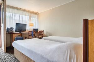 圣迪济耶Kyriad Direct Saint-Dizier的酒店客房设有两张床和一张书桌及电视