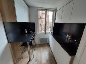 斯特拉斯堡Les appartements Place de la Cathédrale的厨房设有黑色柜台和窗户。