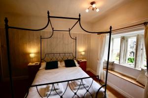 格拉辛顿艾斯菲尔德庄园旅馆的一间卧室设有一张黑色天蓬床和一扇窗户。