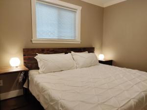 温哥华Private Suite w King Bed, Ground Level, Naturally Bright的一间卧室配有一张带两盏灯的大型白色床。