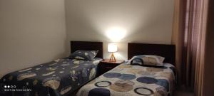 塔里哈Departamento El-Shaddai的一间卧室设有两张床和一张桌子上的台灯。