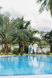 TrâpeăngSS Villa & Resort的站在游泳池边缘的男人和女人