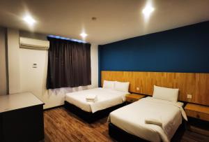 哥打京那巴鲁3-Plus Hotel的酒店客房设有两张床和蓝色的墙壁。