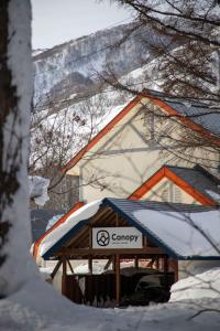 小谷村Canopy Lodge - Boutique Lodge at Hakuba Cortina的雪覆盖的建筑前的标志