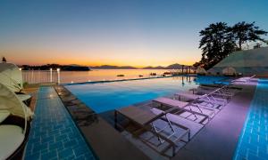 泗川艺术度假村水疗和泳池别墅的一个带躺椅的游泳池,日落时分享有海景