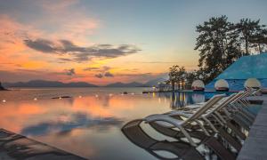泗川艺术度假村水疗和泳池别墅的一个带椅子的游泳池,日落时分享有海景