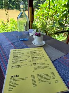 Nongkhiaw曼陀罗欧度假酒店的一张带菜单和一瓶葡萄酒的桌子