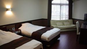 长崎长崎圣保罗酒店的酒店客房,设有两张床和一张沙发