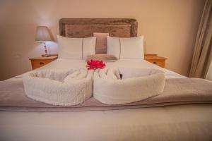 哈拉雷Palm villa的一张带白色毛巾和红色花的床铺