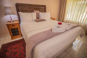 哈拉雷Palm villa的一间卧室配有一张白色大床,床上有鲜花