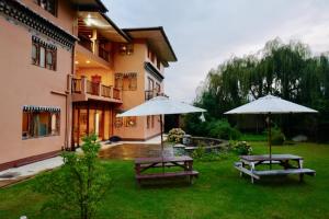 帕罗Taktsang Village Resort的院子里的两张野餐桌和两把遮阳伞