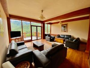 帕罗Taktsang Village Resort的客厅配有皮革家具和大窗户
