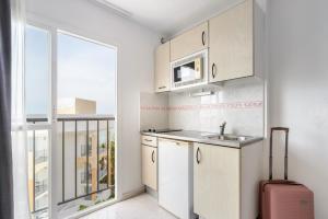 圣安东尼奥Vibra Calima Apartamentos - Adults only的厨房配有白色橱柜、水槽和窗户。