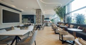 马德里伊鲁尼阿垂姆康福特尔酒店的餐厅设有桌椅和大窗户。