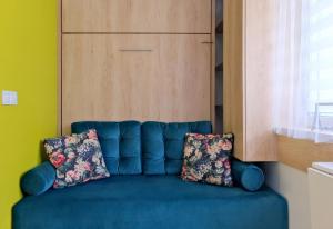 格但斯克Pokój 24E的一张蓝色的沙发,配有两个枕头,位于房间里