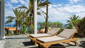 马斯帕洛马斯Deva Beach Boutique Apartment的两把躺椅位于种有棕榈树和海洋的庭院