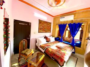 斋沙默尔Hotel Murad Haveli Jaisalmer的一间卧室配有一张床、一张桌子和一个窗户。