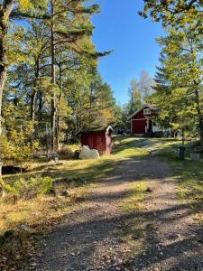 斯德哥尔摩Charmigt hus på Vindö的一条通往红谷仓和树木的土路