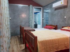 Ban Pak NamBaan Thabthong Homestay (บ้านทับทอง โฮมสเตย์)的一间卧室设有两张床和窗户。