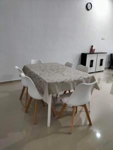 哥打巴鲁Wipah Guest House in Kampung Lundang, Kota Bharu的餐桌、白色椅子、桌子和时钟